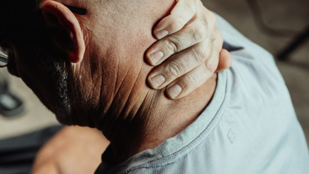 Man holding hand over neck